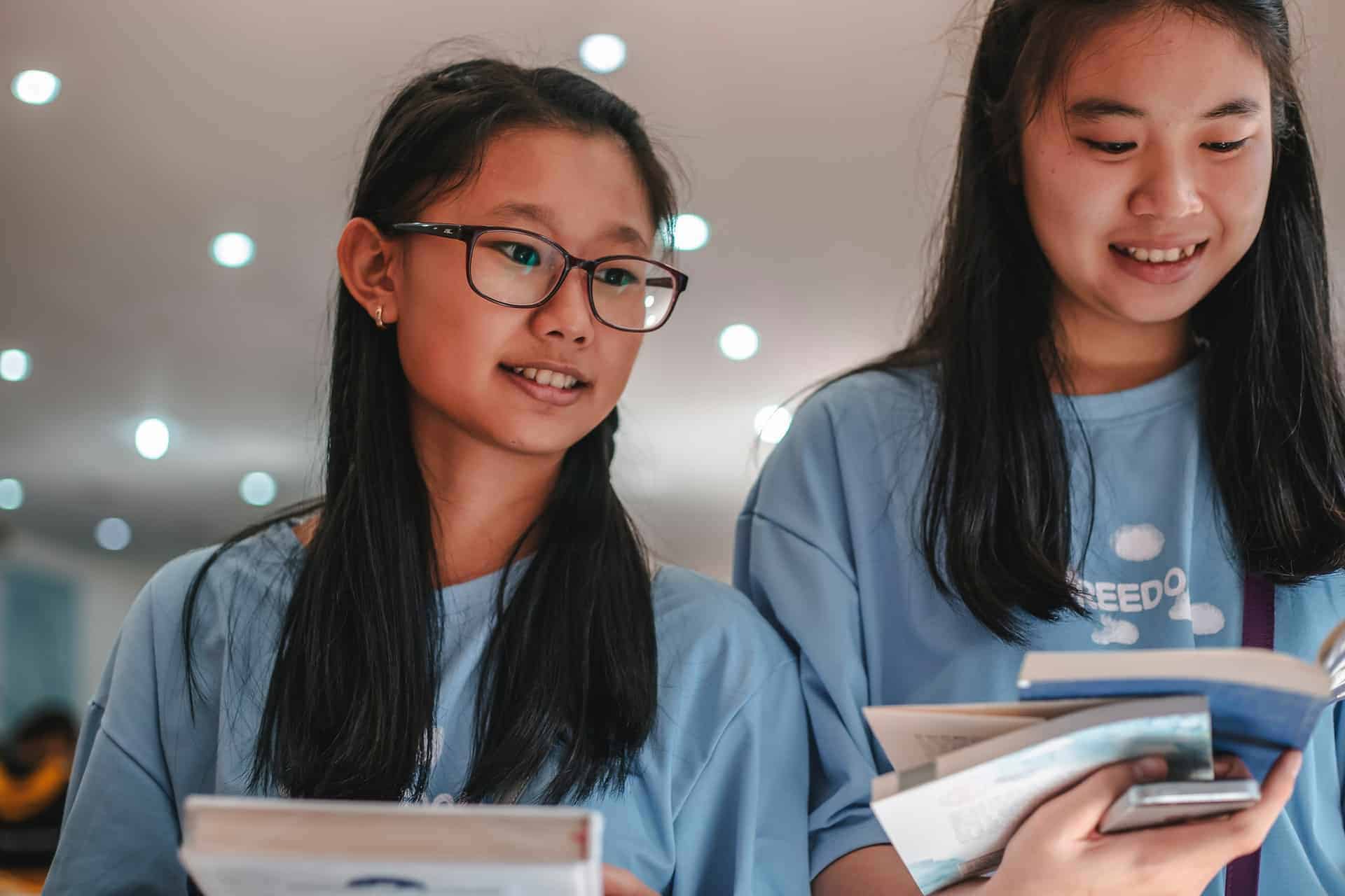 girls wearing blue shirt looking at the books 4058670