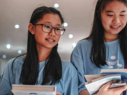girls wearing blue shirt looking at the books 4058670