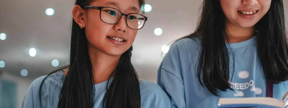 girls wearing blue shirt looking at the books 4058670